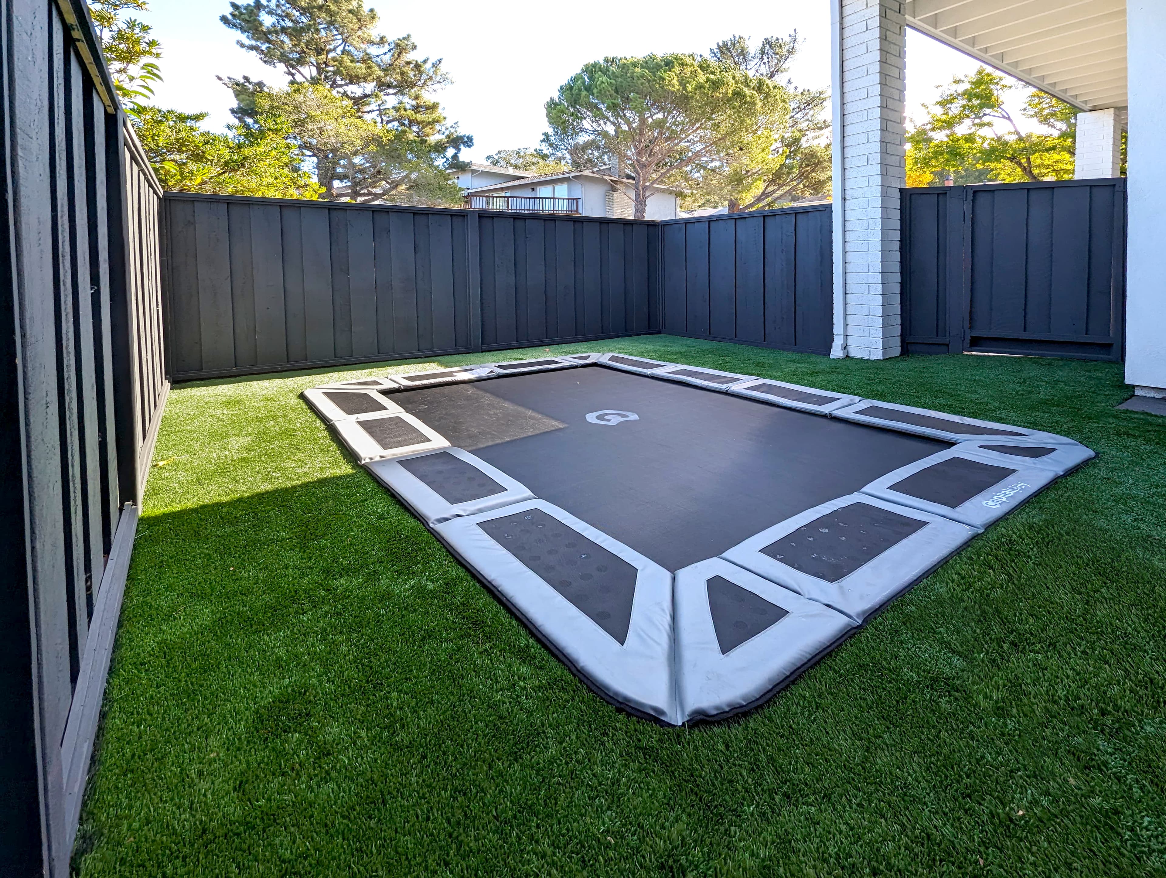 Inground trampoline. Artificial turf. Stained fence.